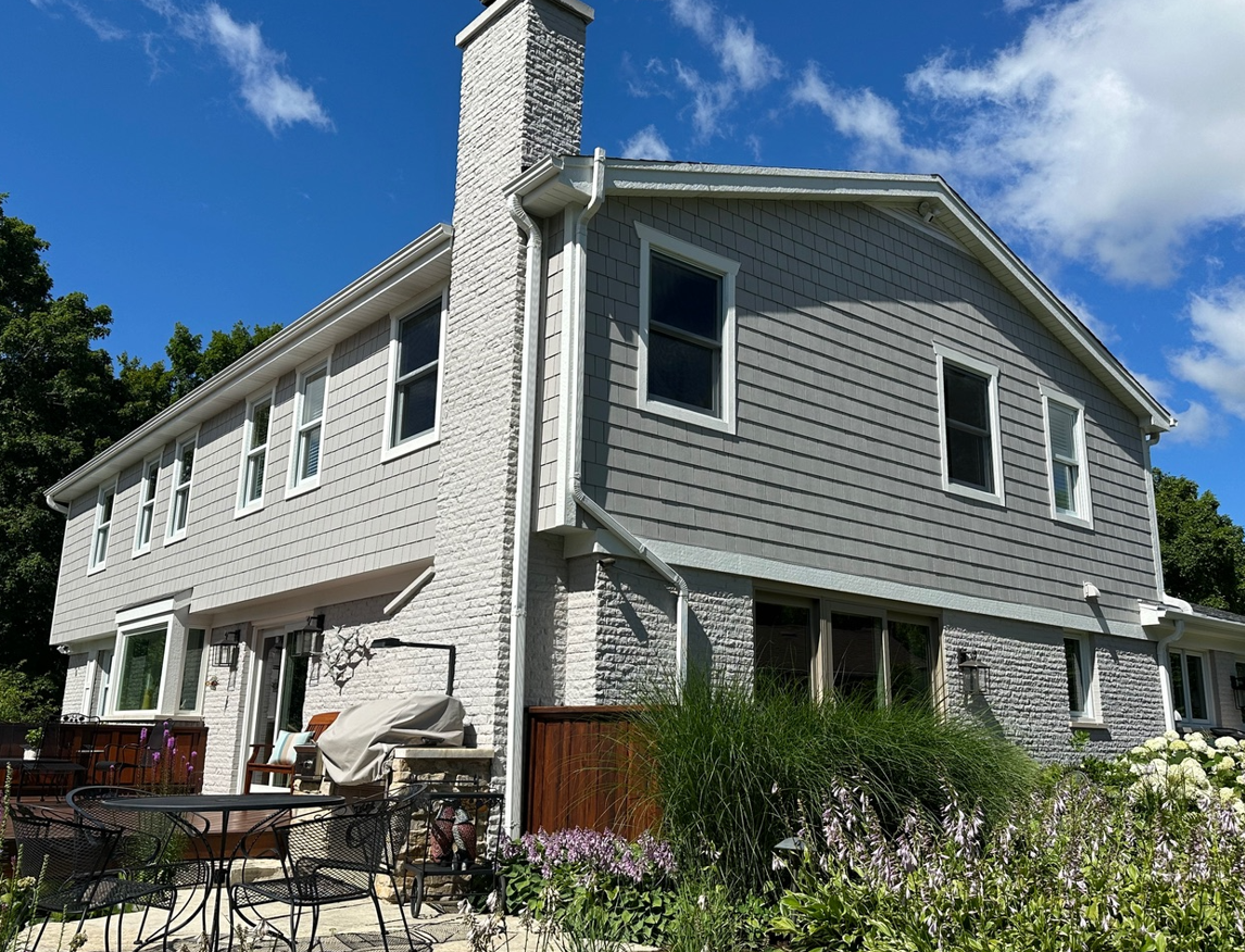 A large house with a lot of windows and a chimney on a sunny day.