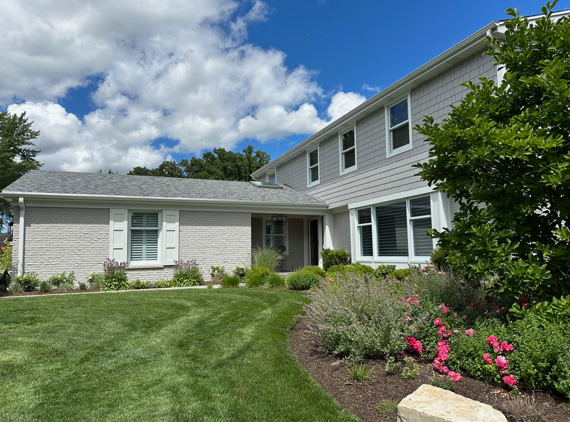 A large white house with a lush green lawn in front of it.