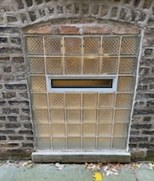 Glass block window with small rectangular window in brick building.