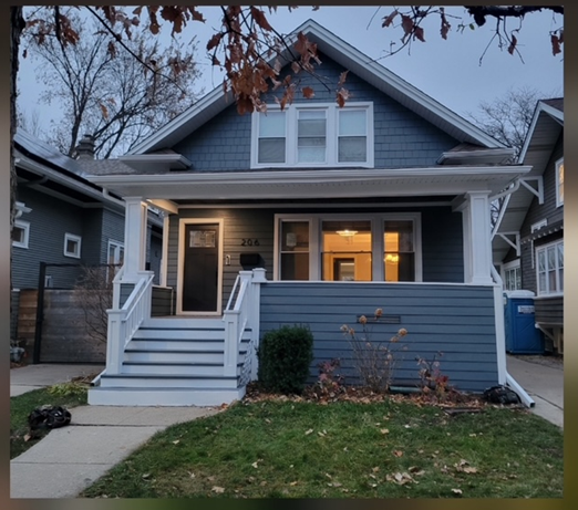 Green two-story house with green trim and a porch.