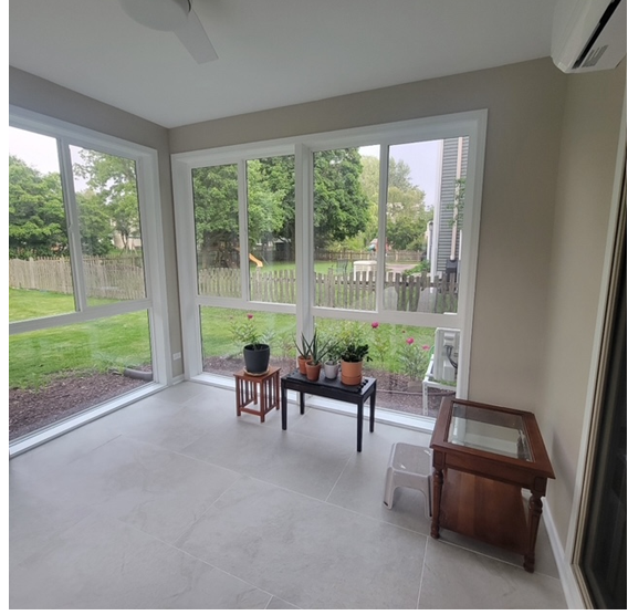 A room with a lot of windows and a table with potted plants on it
