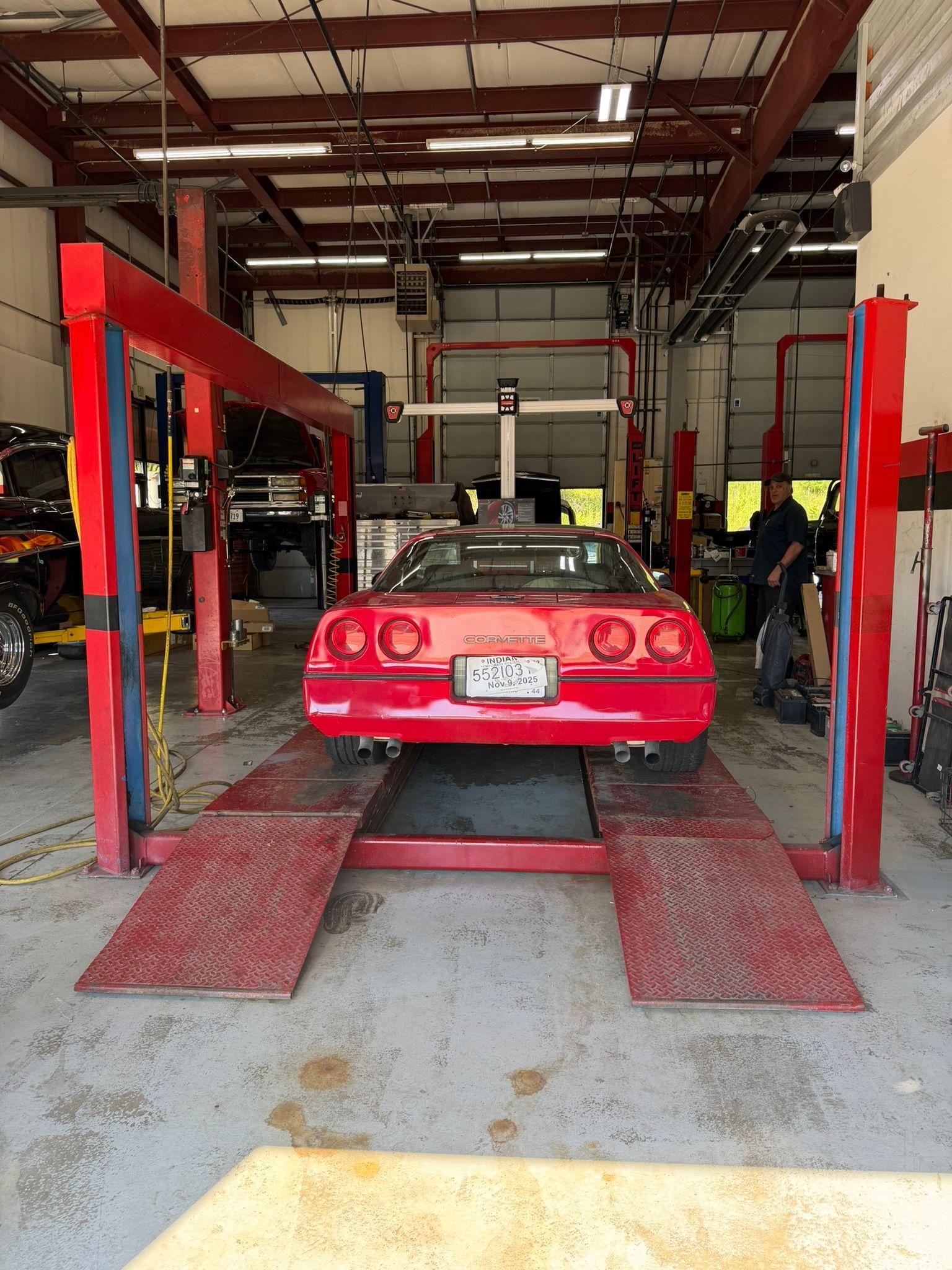 Red sports car on a vehicle lift inside an auto repair shop