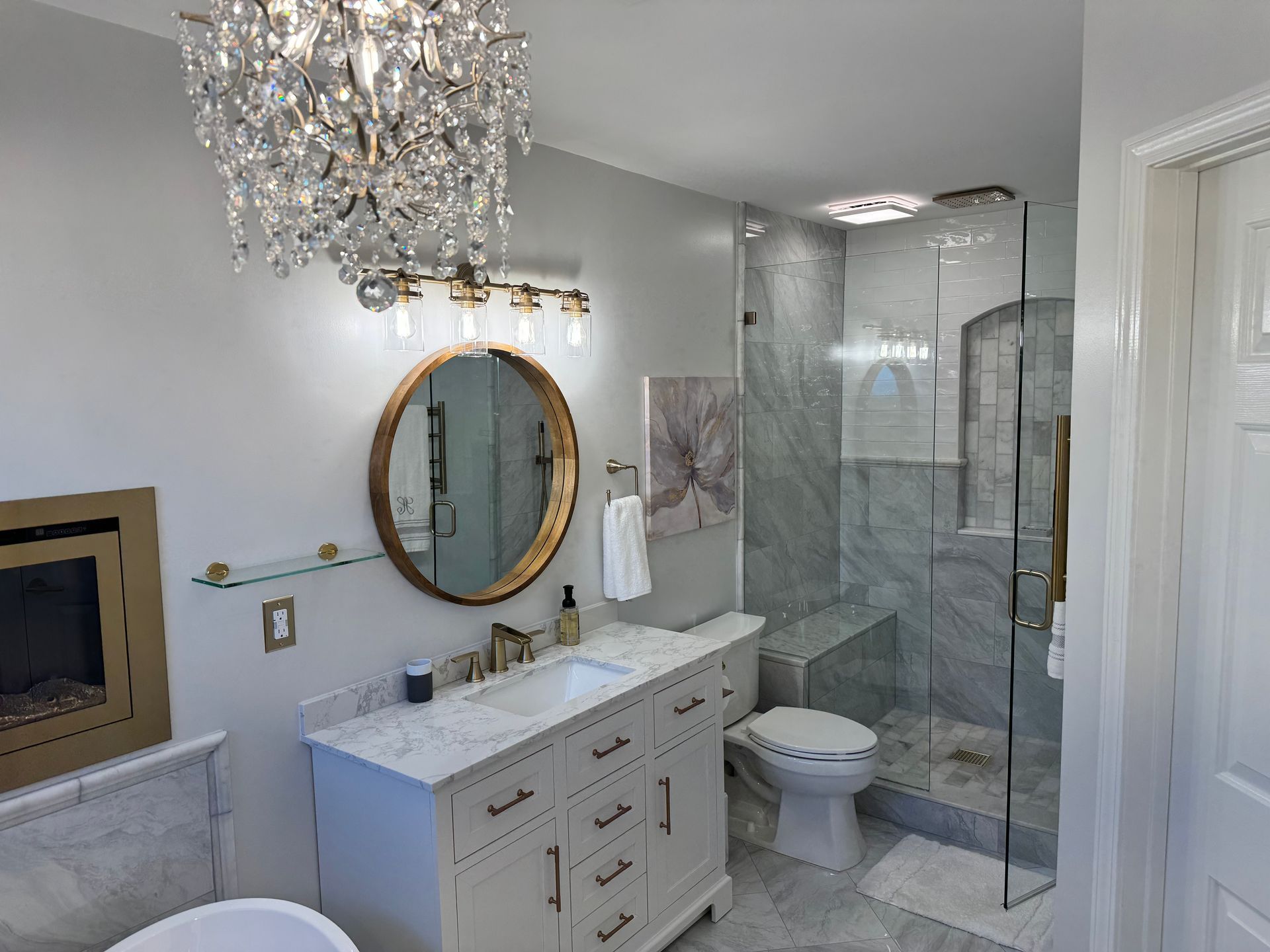 A bathroom with a sink , toilet , shower and chandelier.