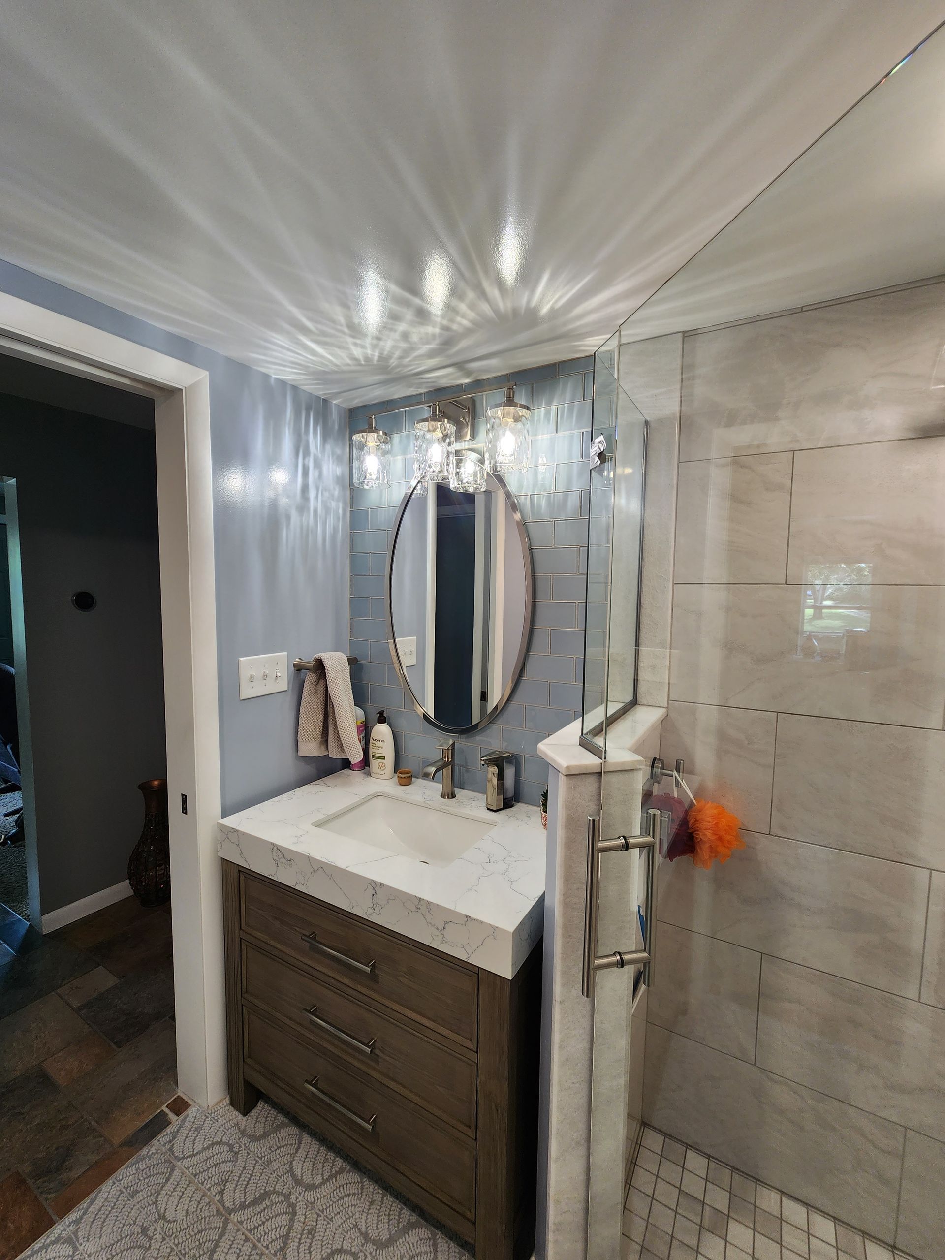 A bathroom with a sink, mirror, and shower.