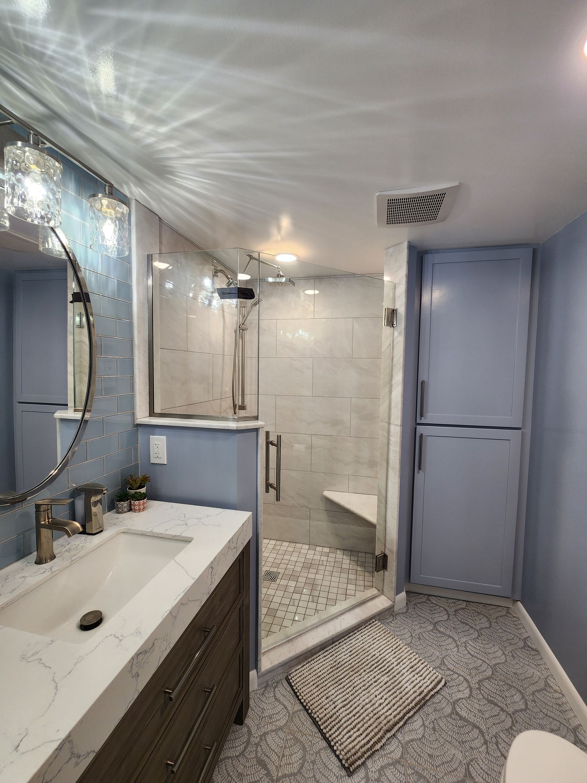 A bathroom with a sink, toilet, shower and mirror.