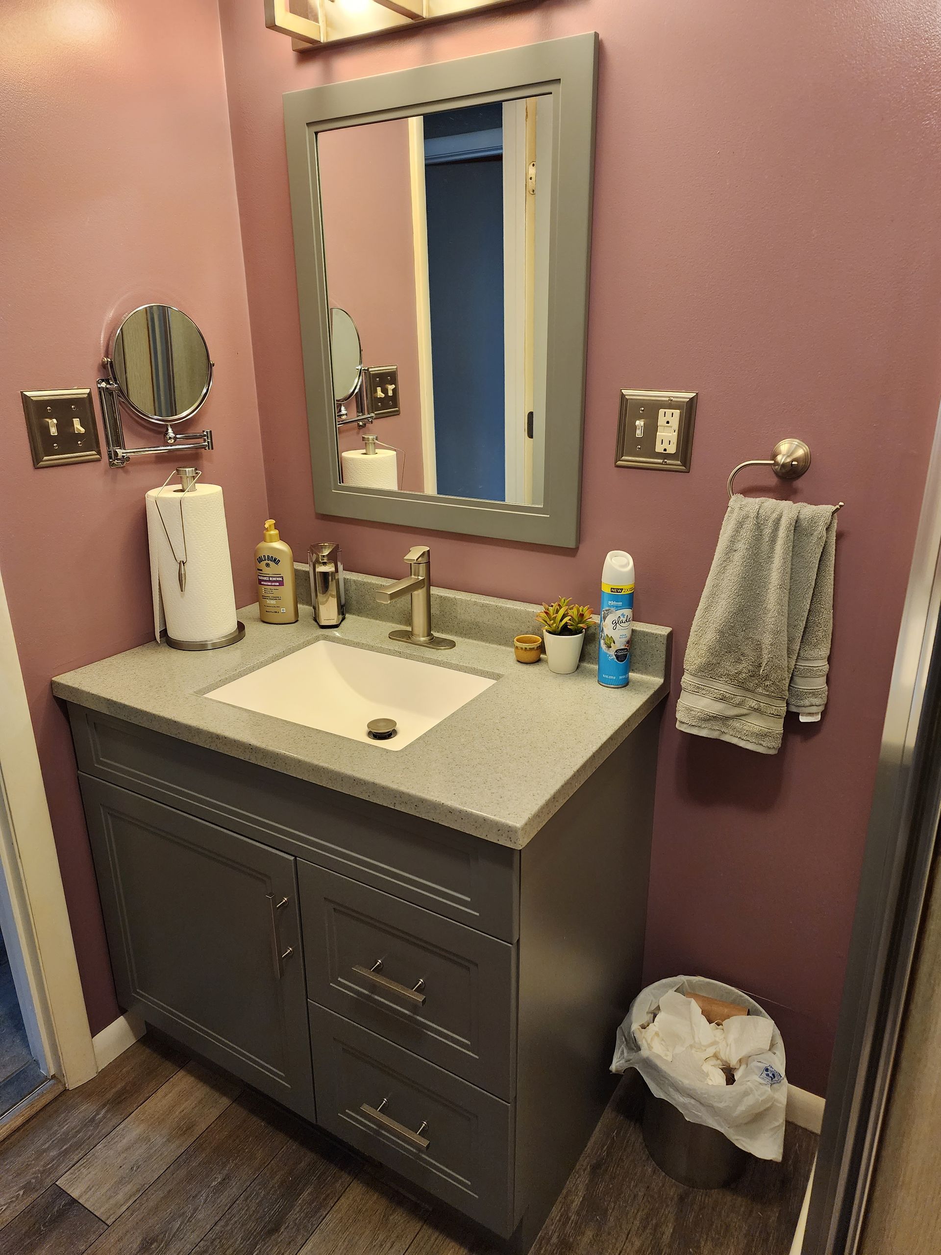 A bathroom with a sink, mirror, and trash can.