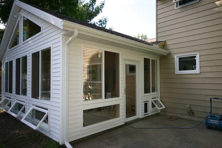 A house with a screened in porch on the side of it.