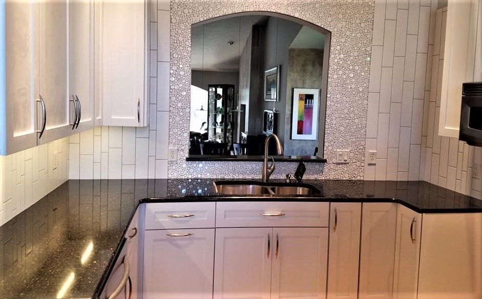 A kitchen with white cabinets and black counter tops