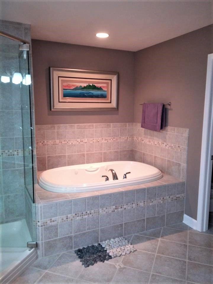 A bathtub in a bathroom with a picture on the wall above it.