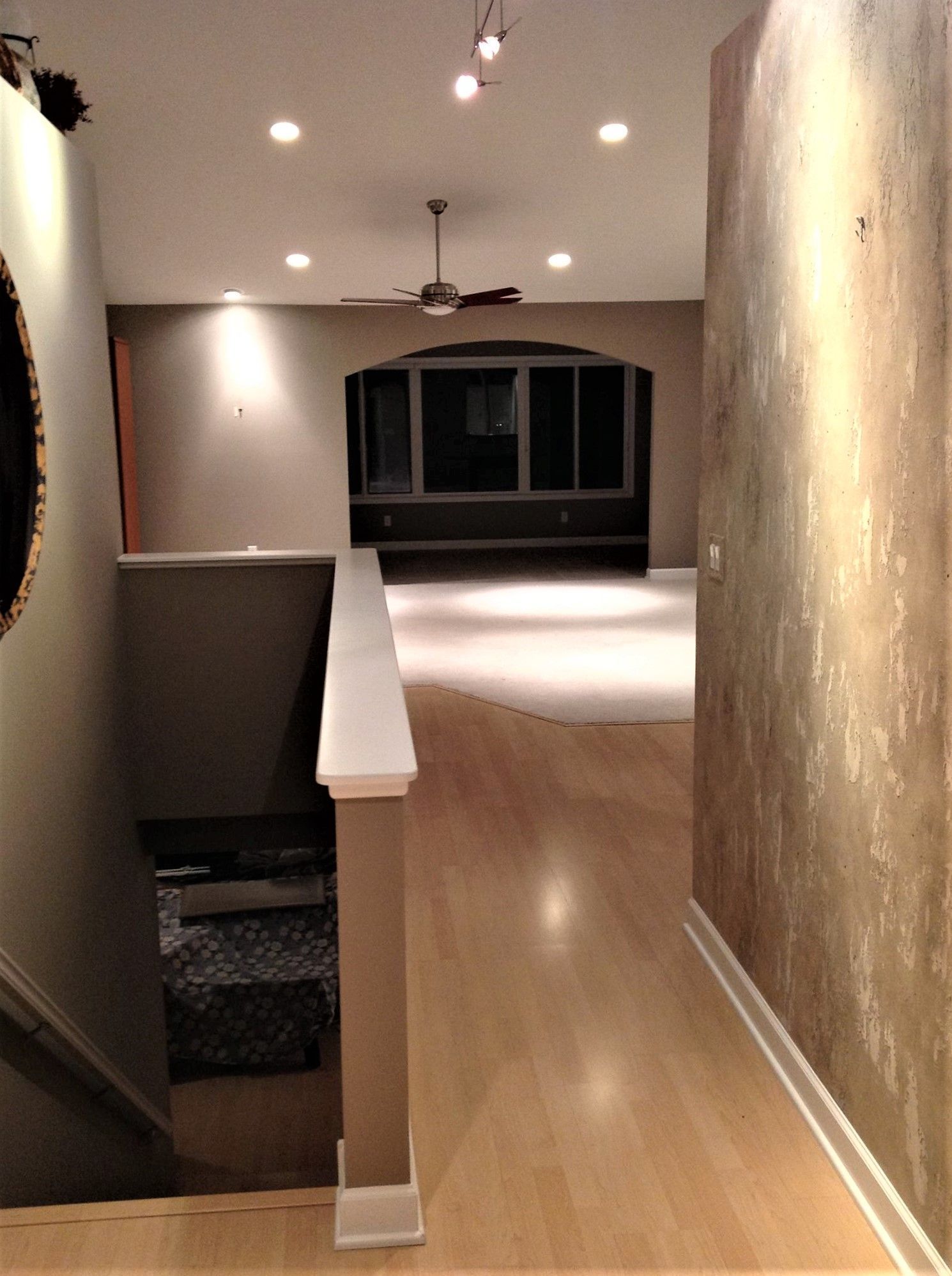 A hallway with hardwood floors and a ceiling fan