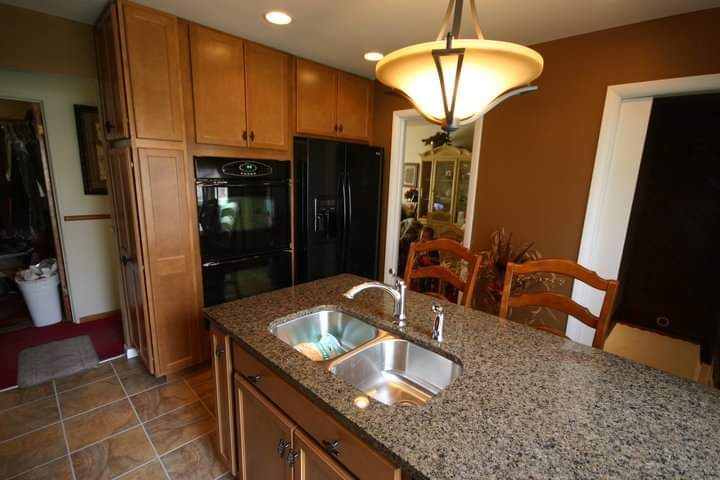 A kitchen with two sinks and a refrigerator