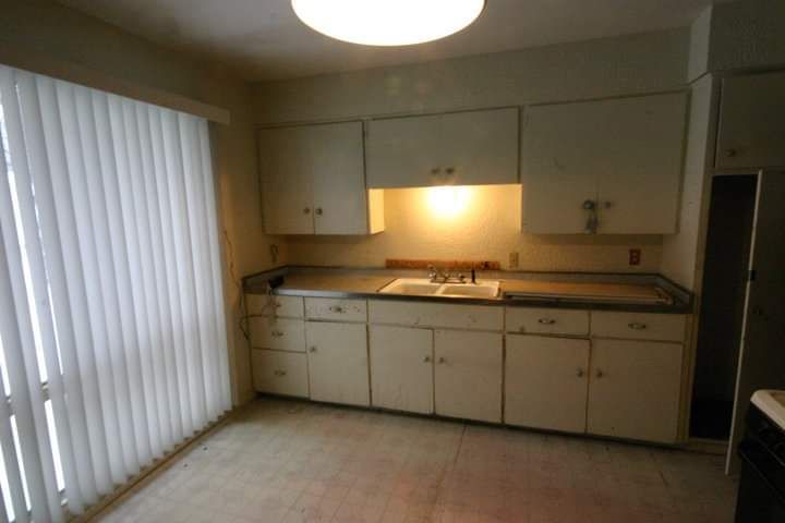 A kitchen with white cabinets and black counter tops