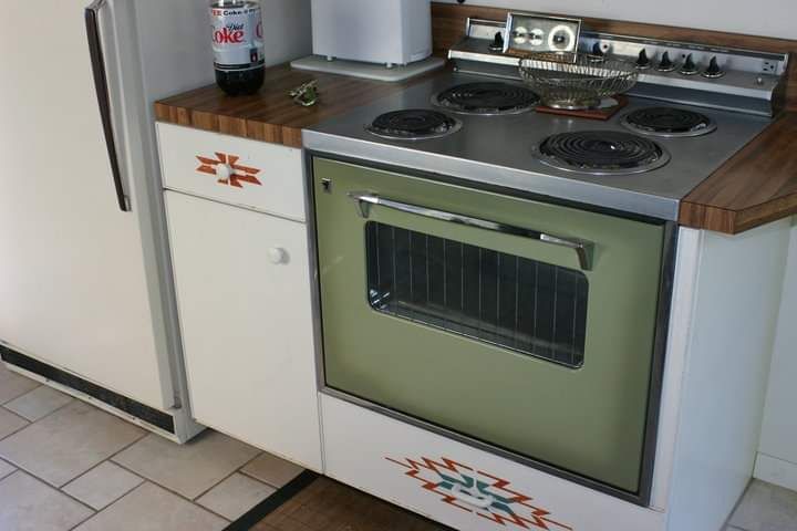 A kitchen with a green stove and a white refrigerator