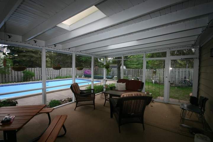 A screened in porch with a swimming pool in the background