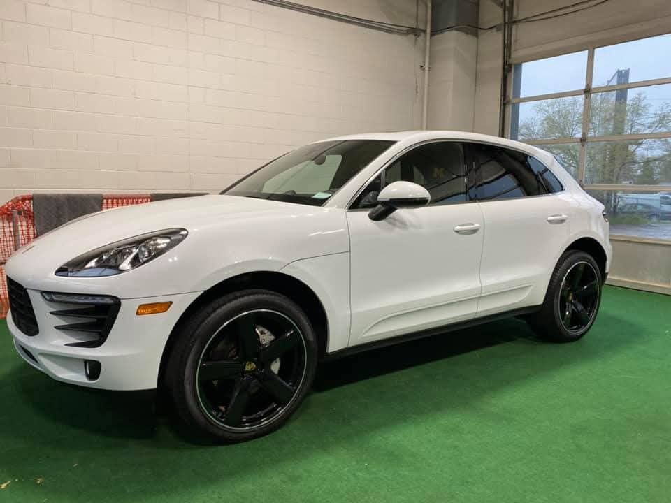 White Porsche SUV with black rims parked inside a building.