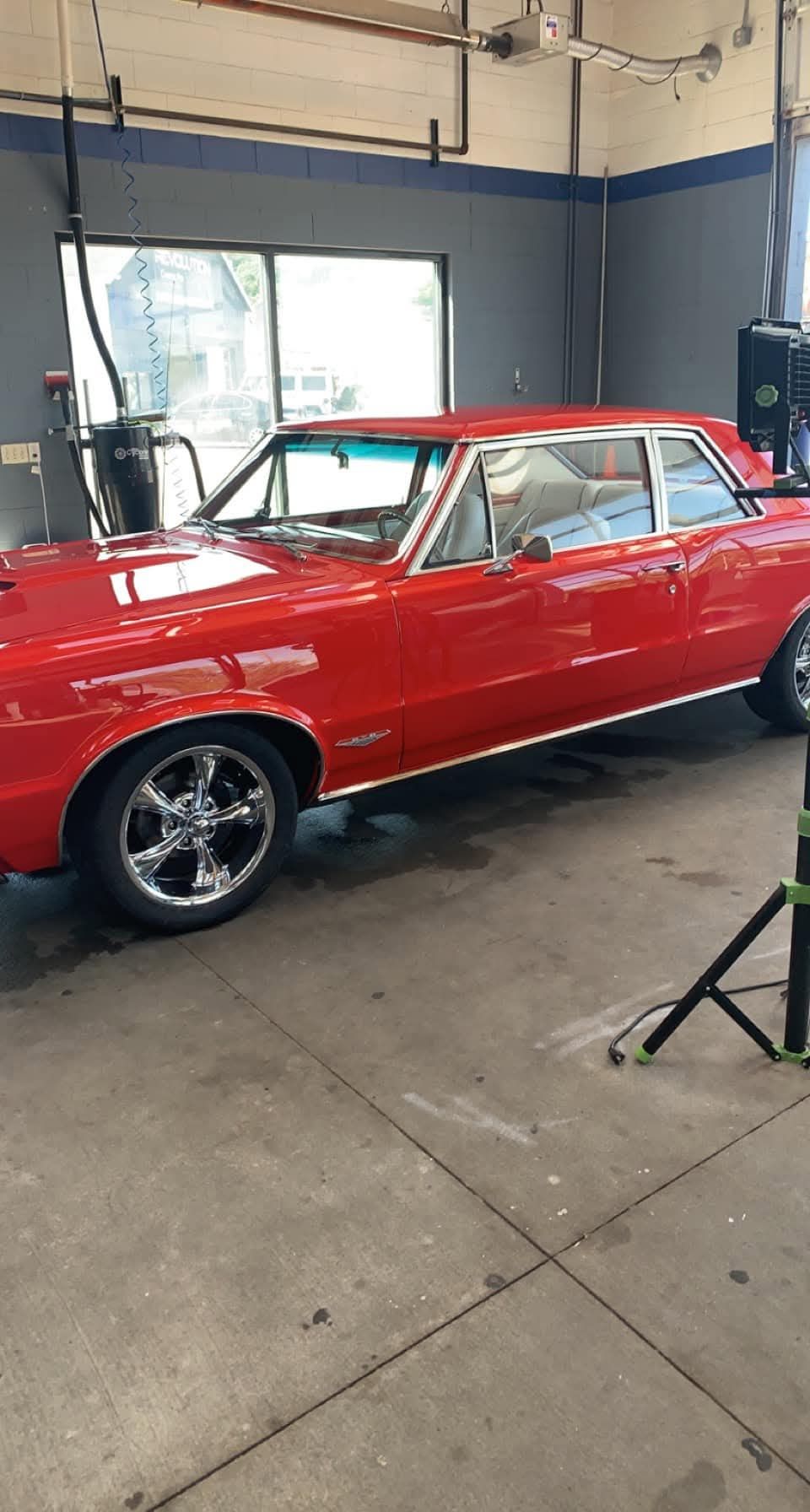 Red classic car on chrome wheels inside a garage.