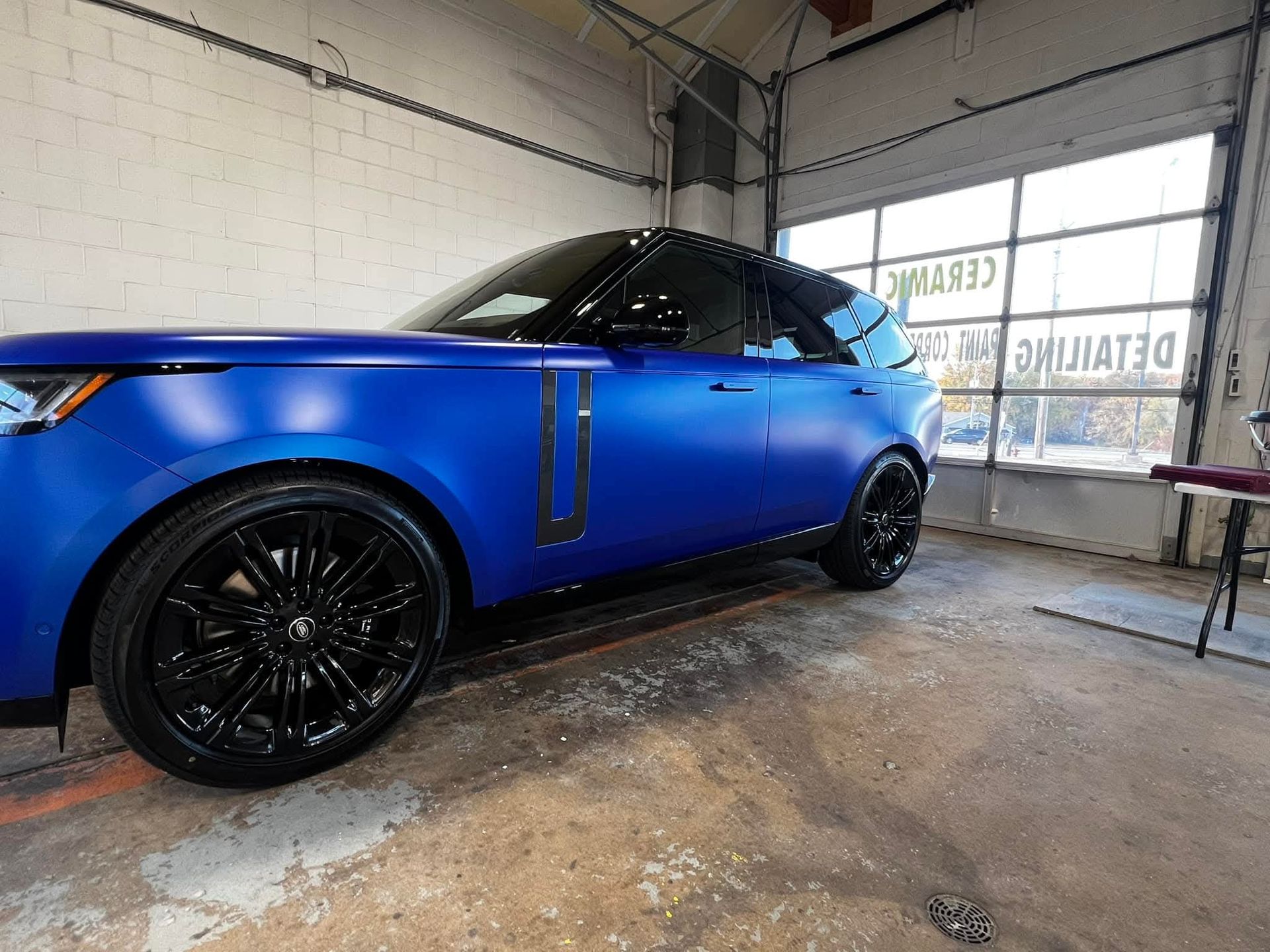 Blue Range Rover with black rims in a garage.