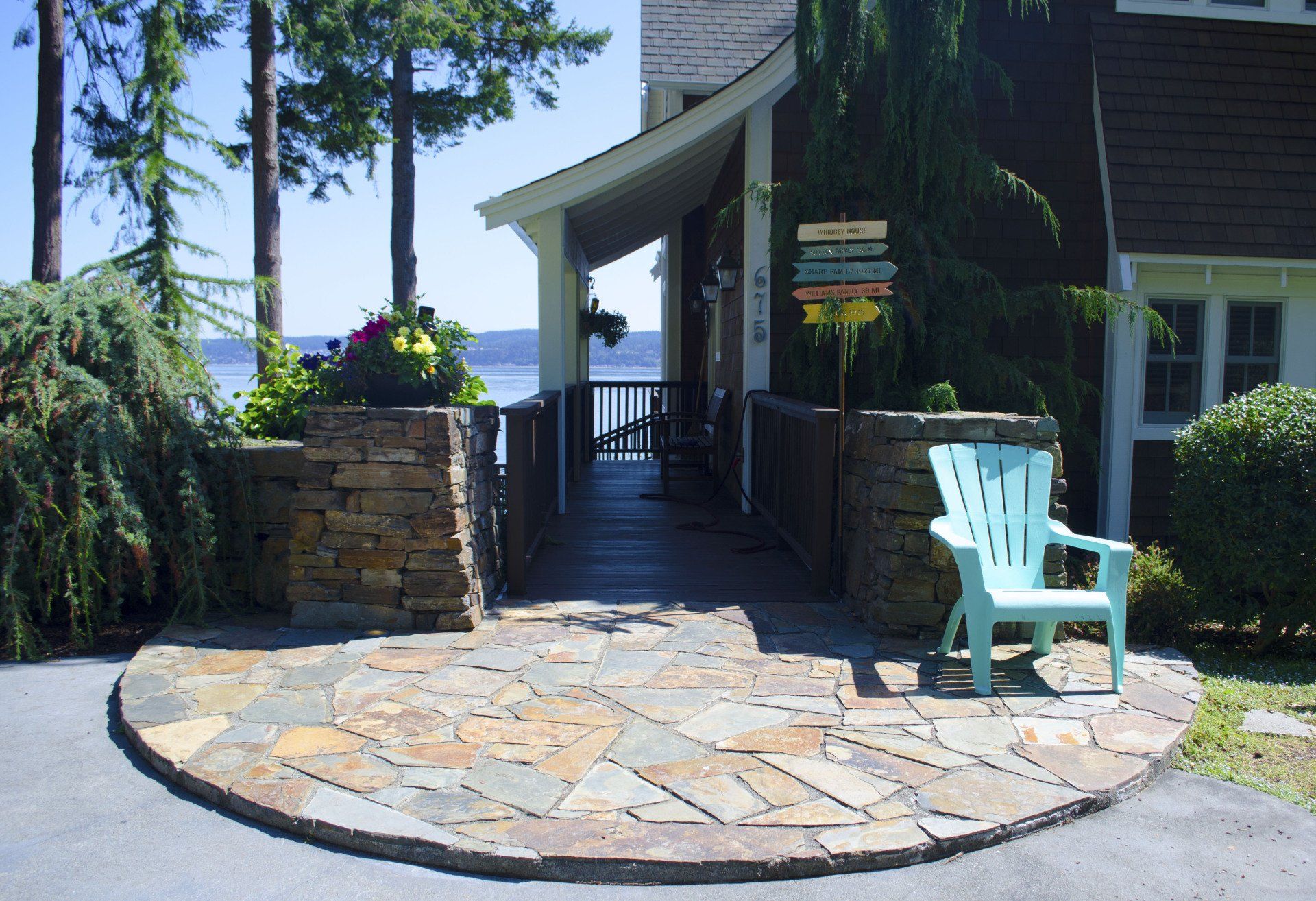 A blue chair sits on a stone patio in front of a house