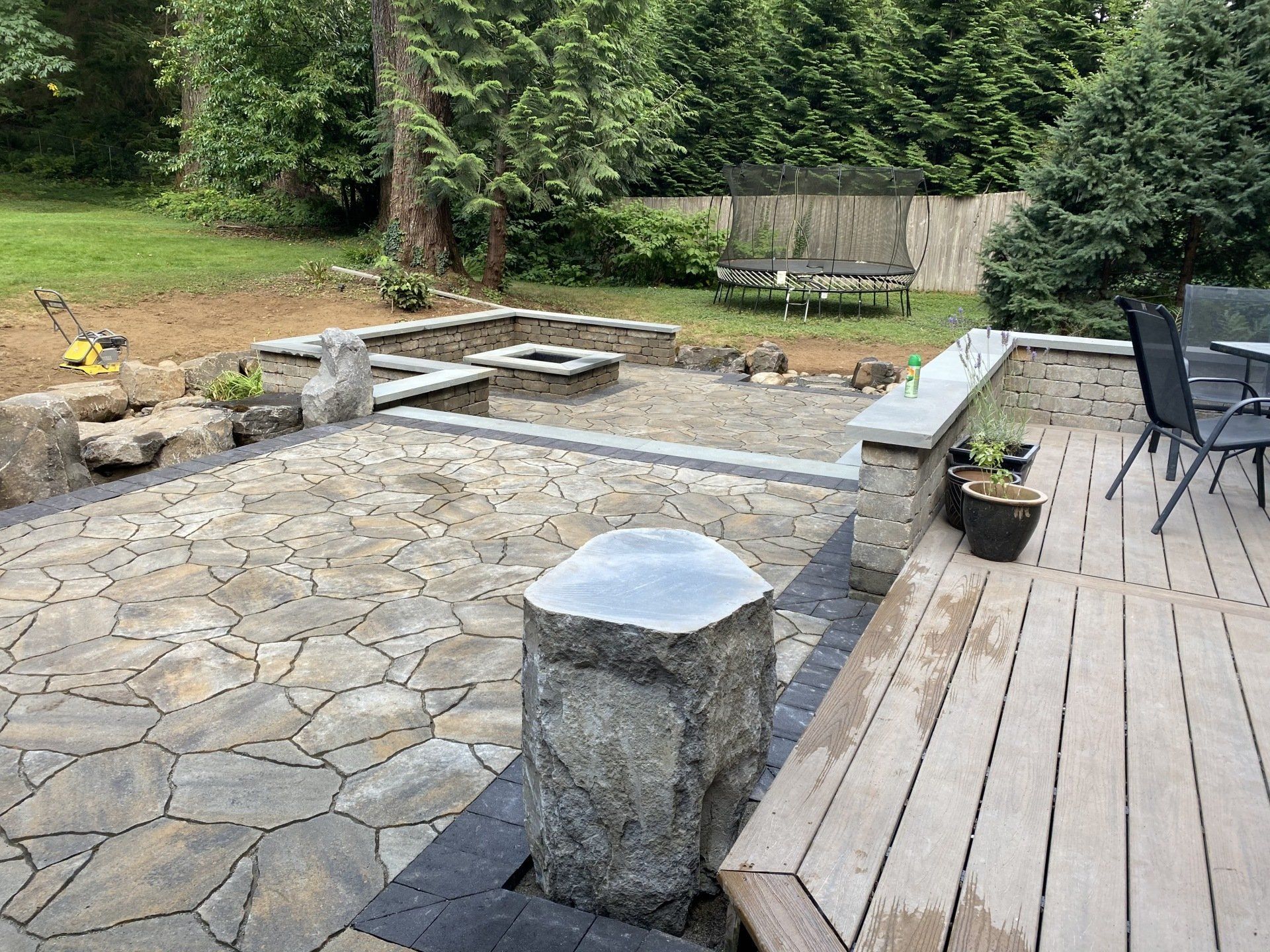 A wooden deck with a stone patio and a fire pit.