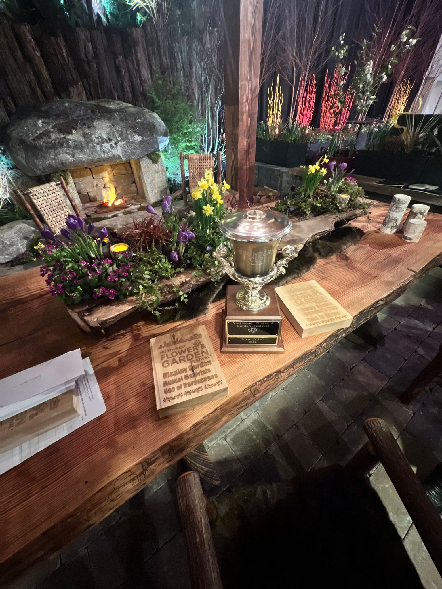 A wooden table with flowers and a trophy on it.