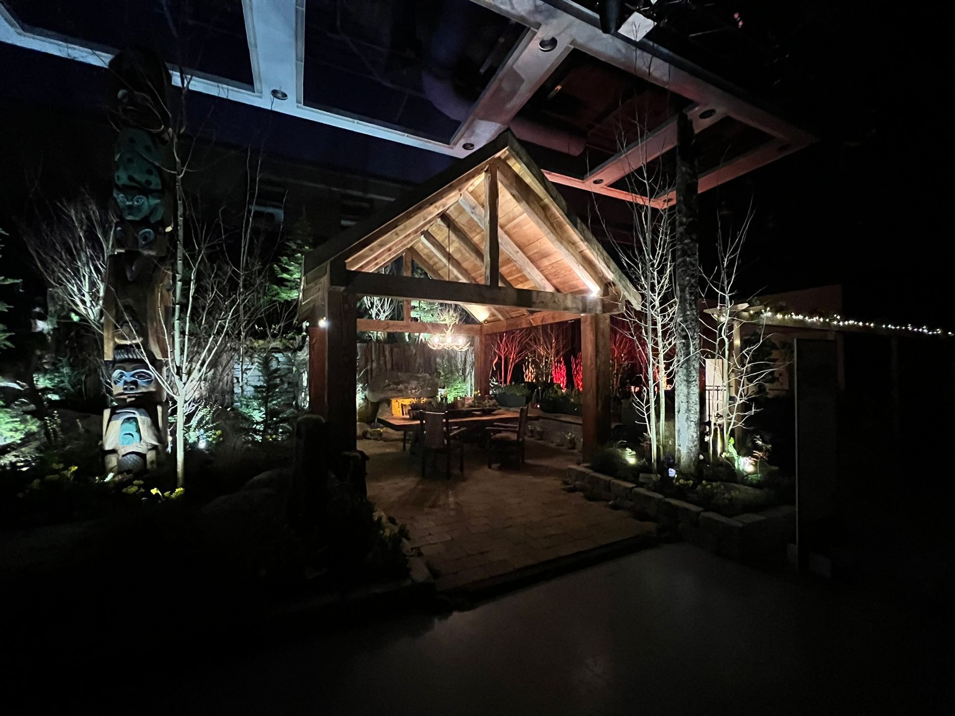 A wooden gazebo is lit up at night in a garden.