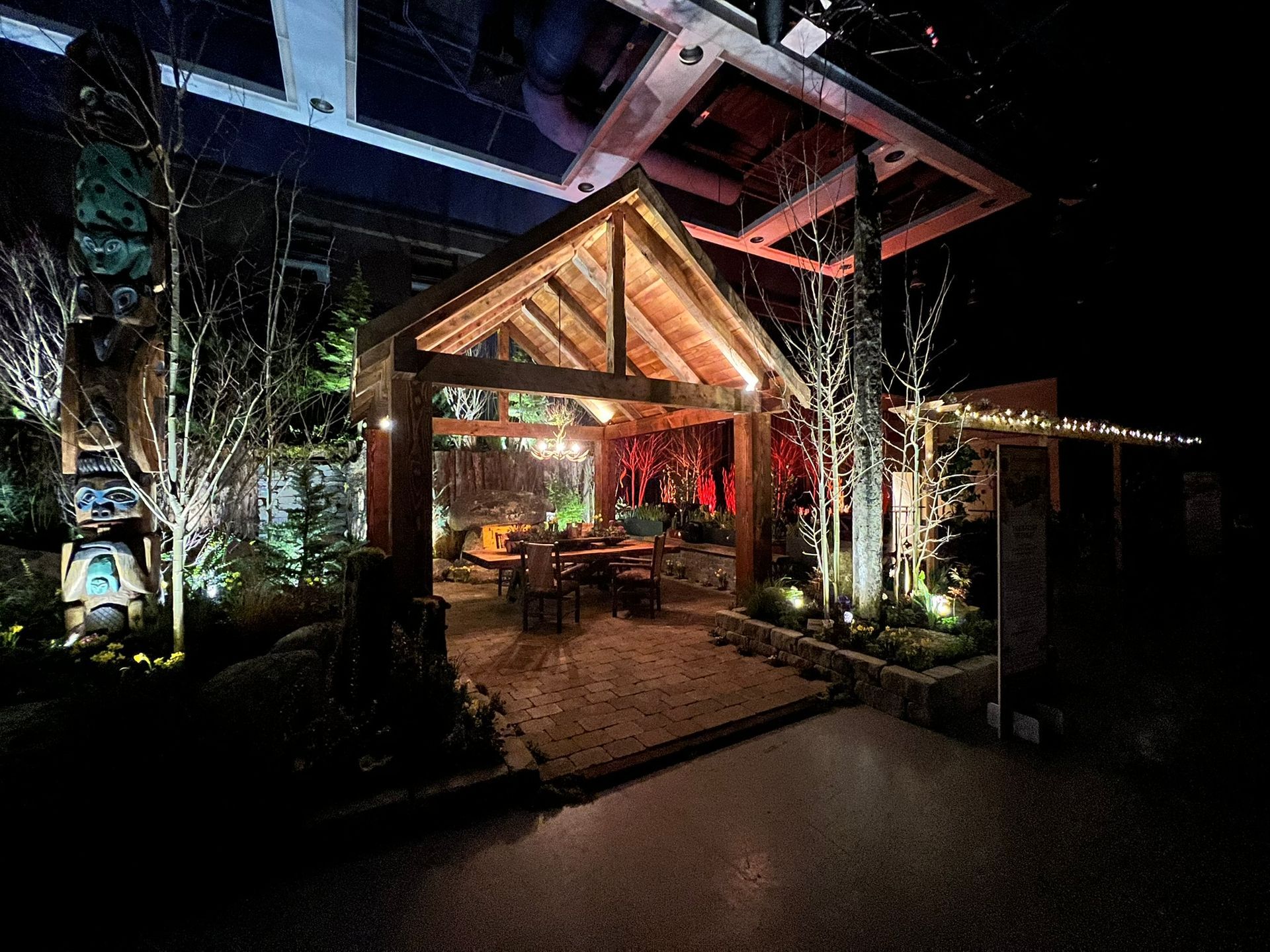 A wooden gazebo is lit up at night in a garden.