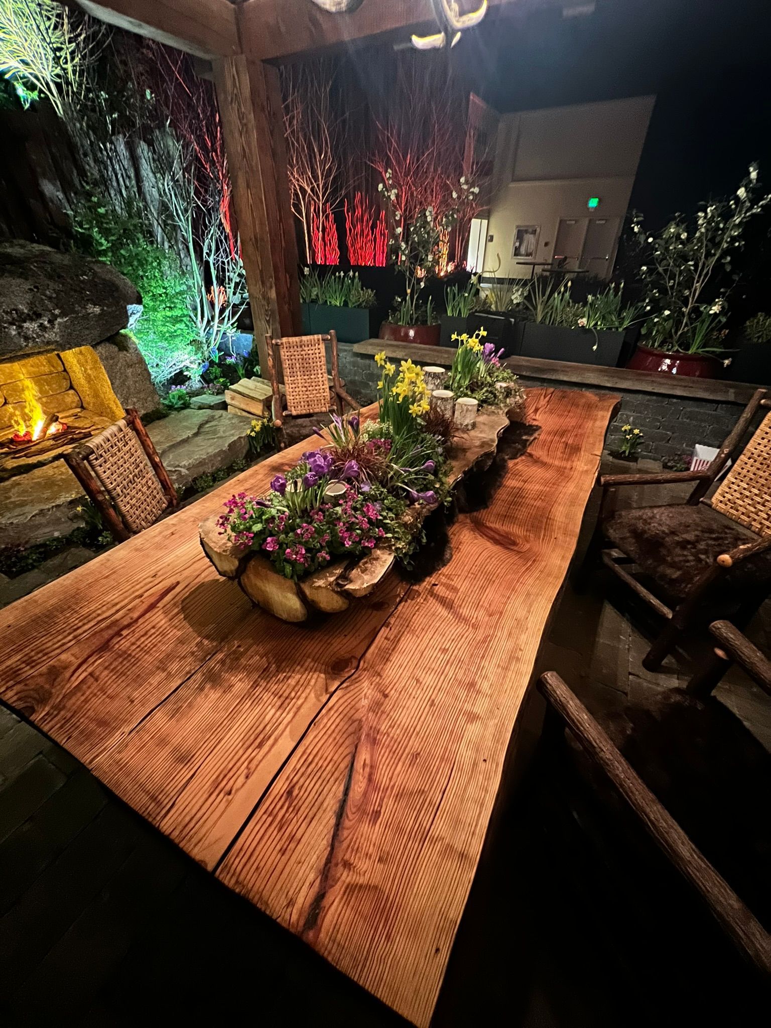 A wooden table with a bowl of flowers on top of it.