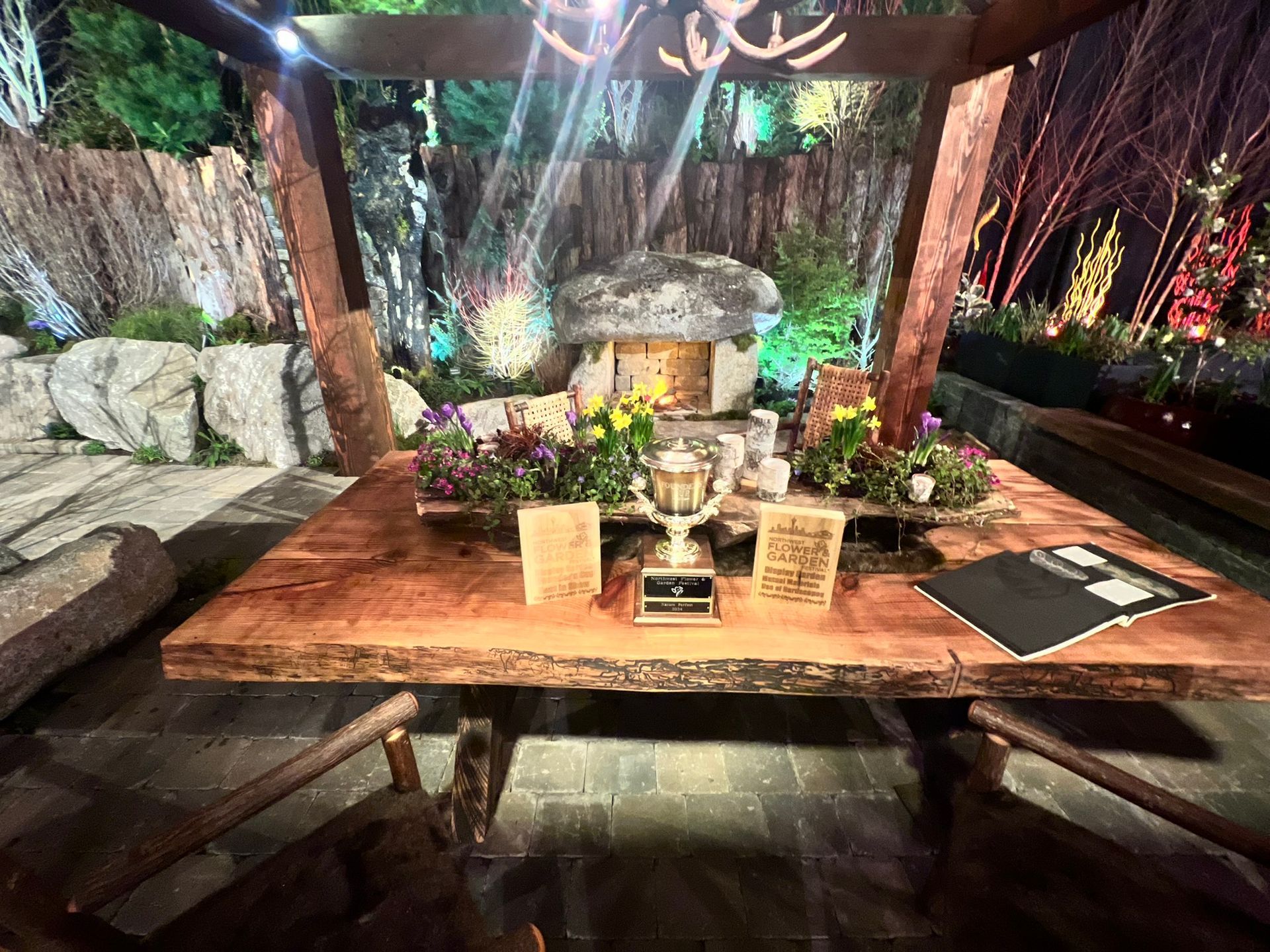 A wooden table with flowers and a trophy on it.