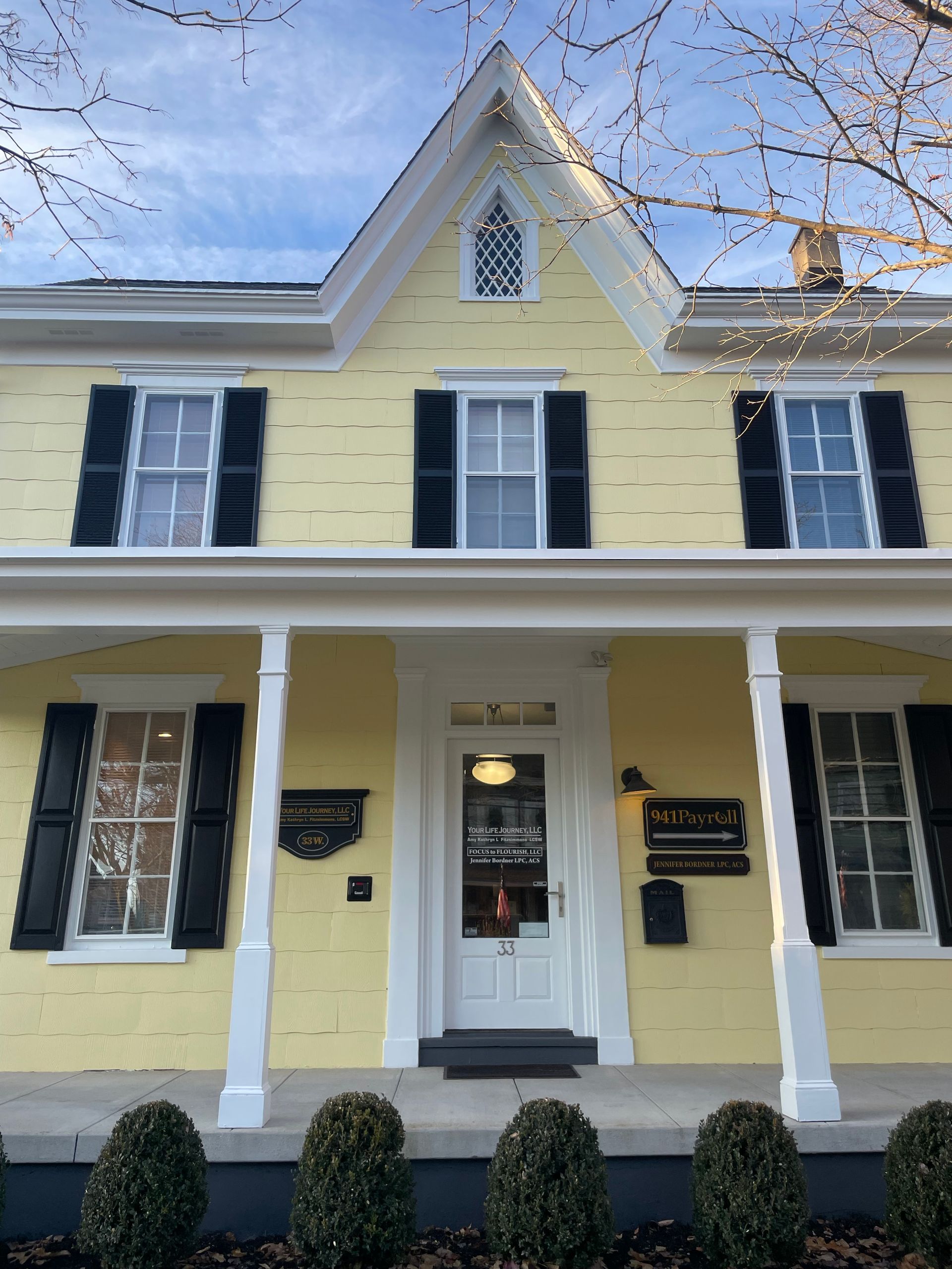 Yellow house with white trim, black shutters, and front porch.