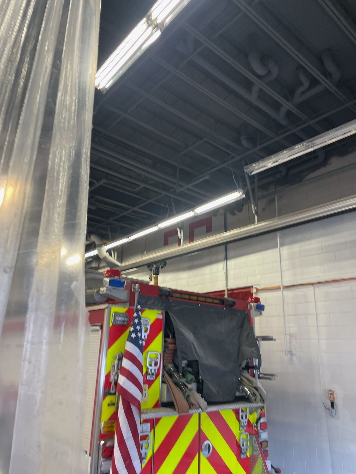 Fire truck inside a bay with plastic sheeting. Red and yellow detailing. American flag attached.