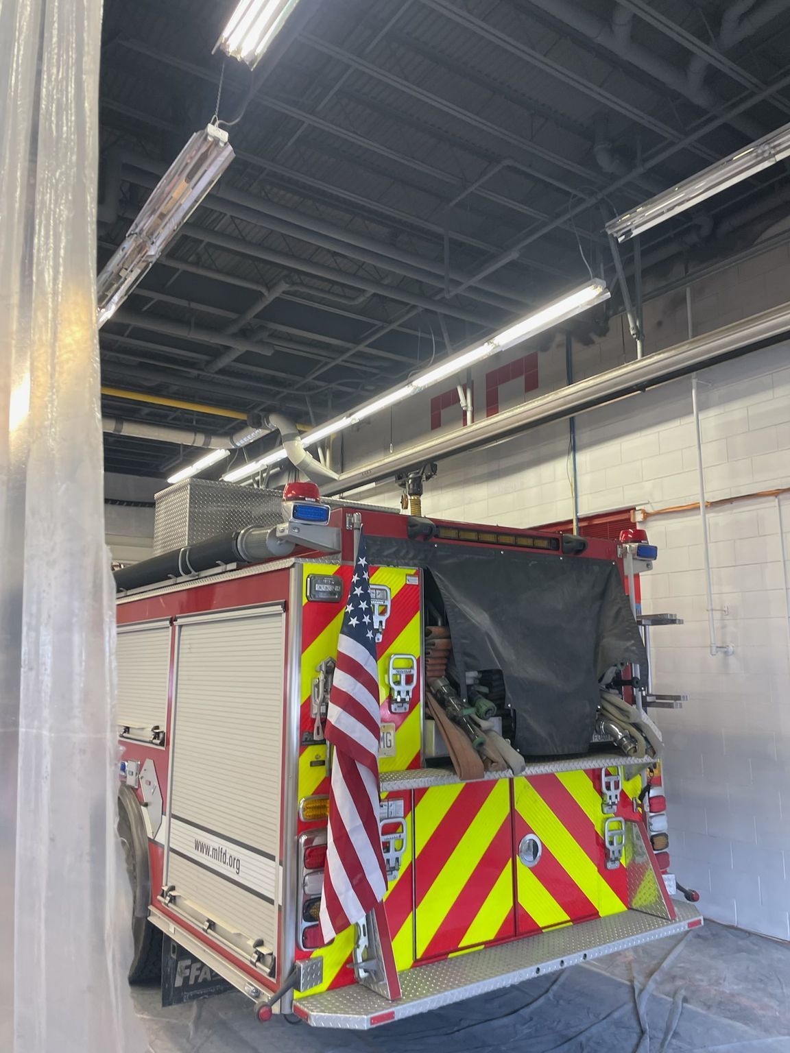 Fire truck inside a garage, American flag displayed on back.