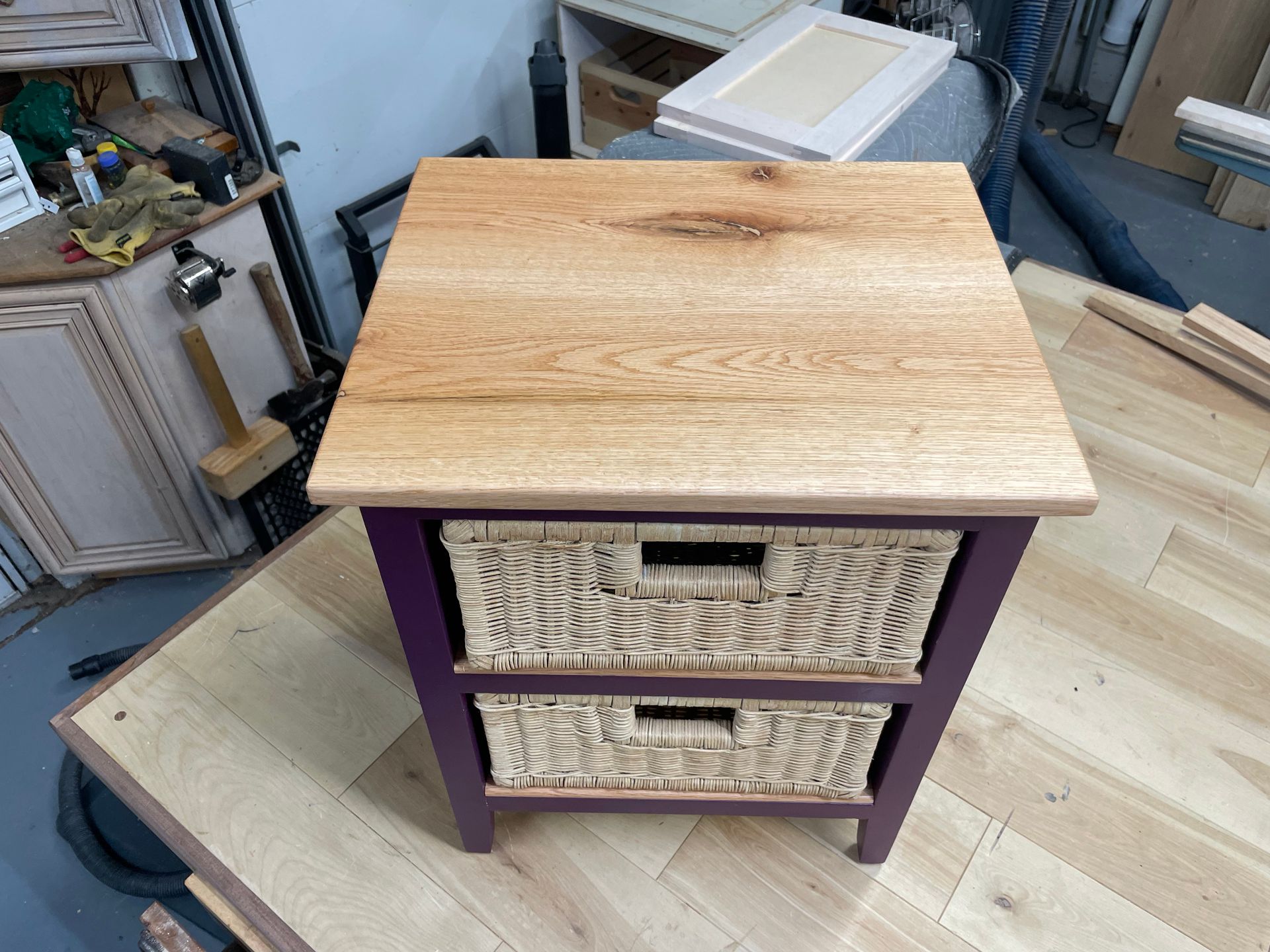 Wooden end table with purple frame, natural wood top, and two wicker drawers.