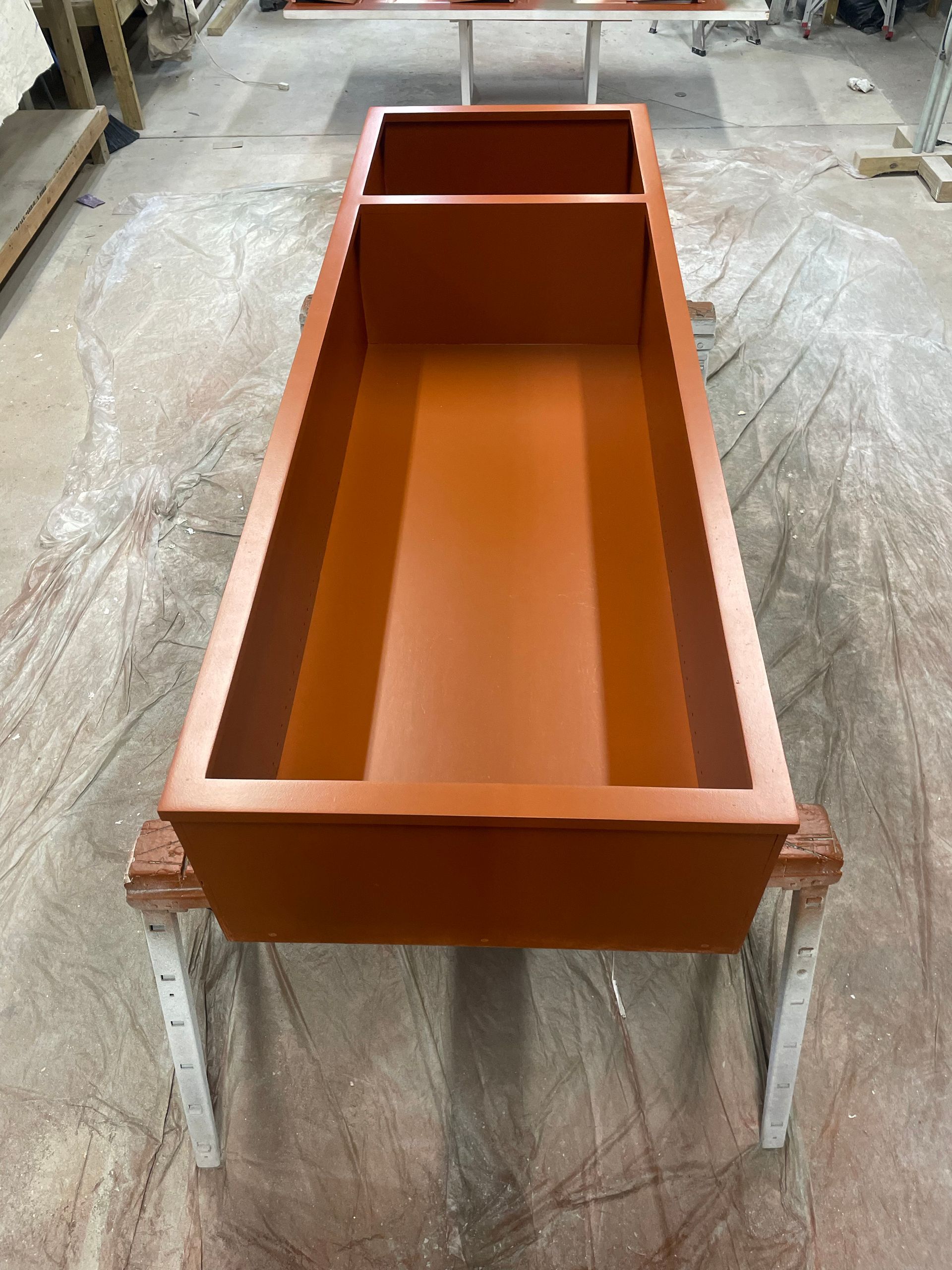 Orange rectangular box with a divider, sitting on sawhorses.