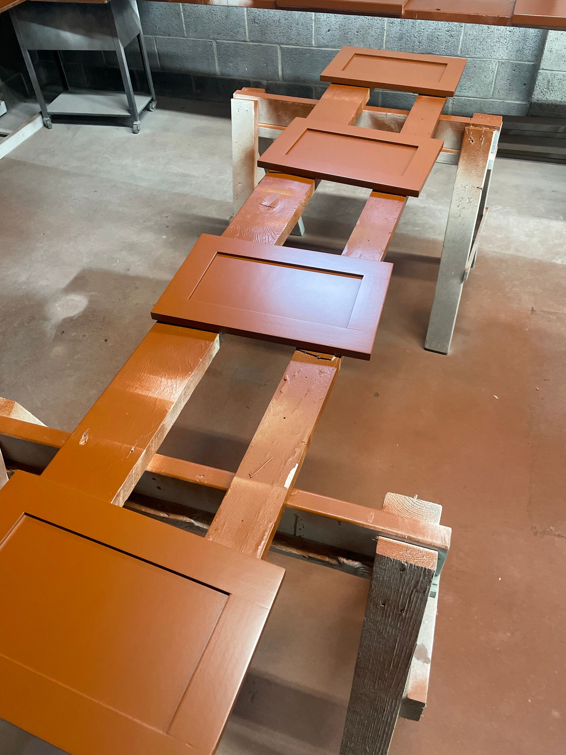 Cabinet doors painted brown, drying on sawhorses in a workshop.