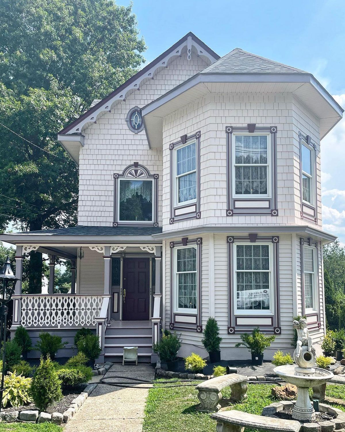 Victorian house with white siding, decorative trim, and small porch. Landscaped front yard.