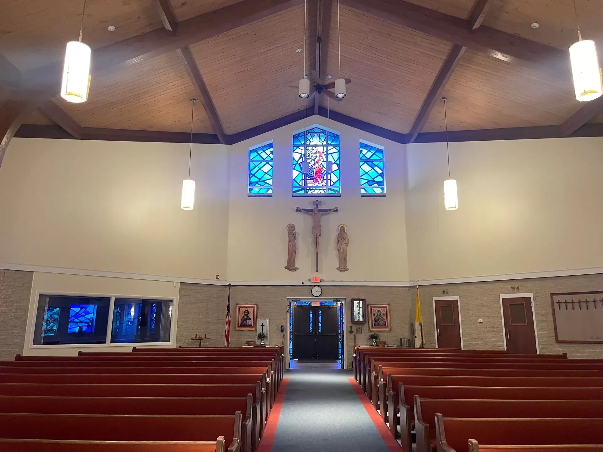 Interior of a church with wooden pews, stained glass, and a crucifix.
