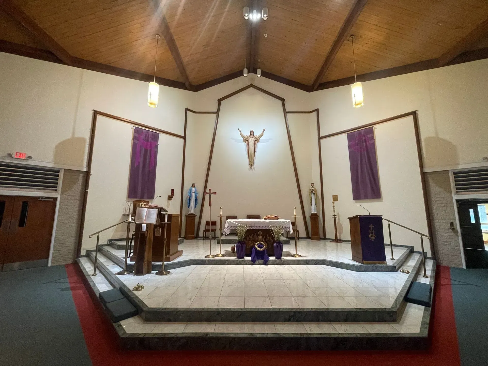 Church interior with an altar, purple drapes, and a statue of Jesus.