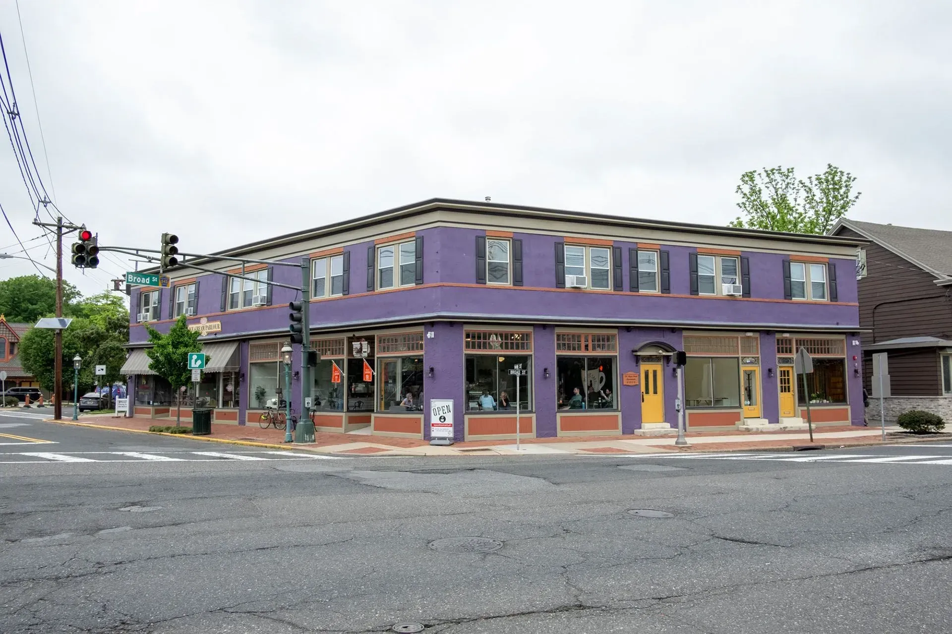 Purple corner building with storefronts at a street intersection on an overcast day.