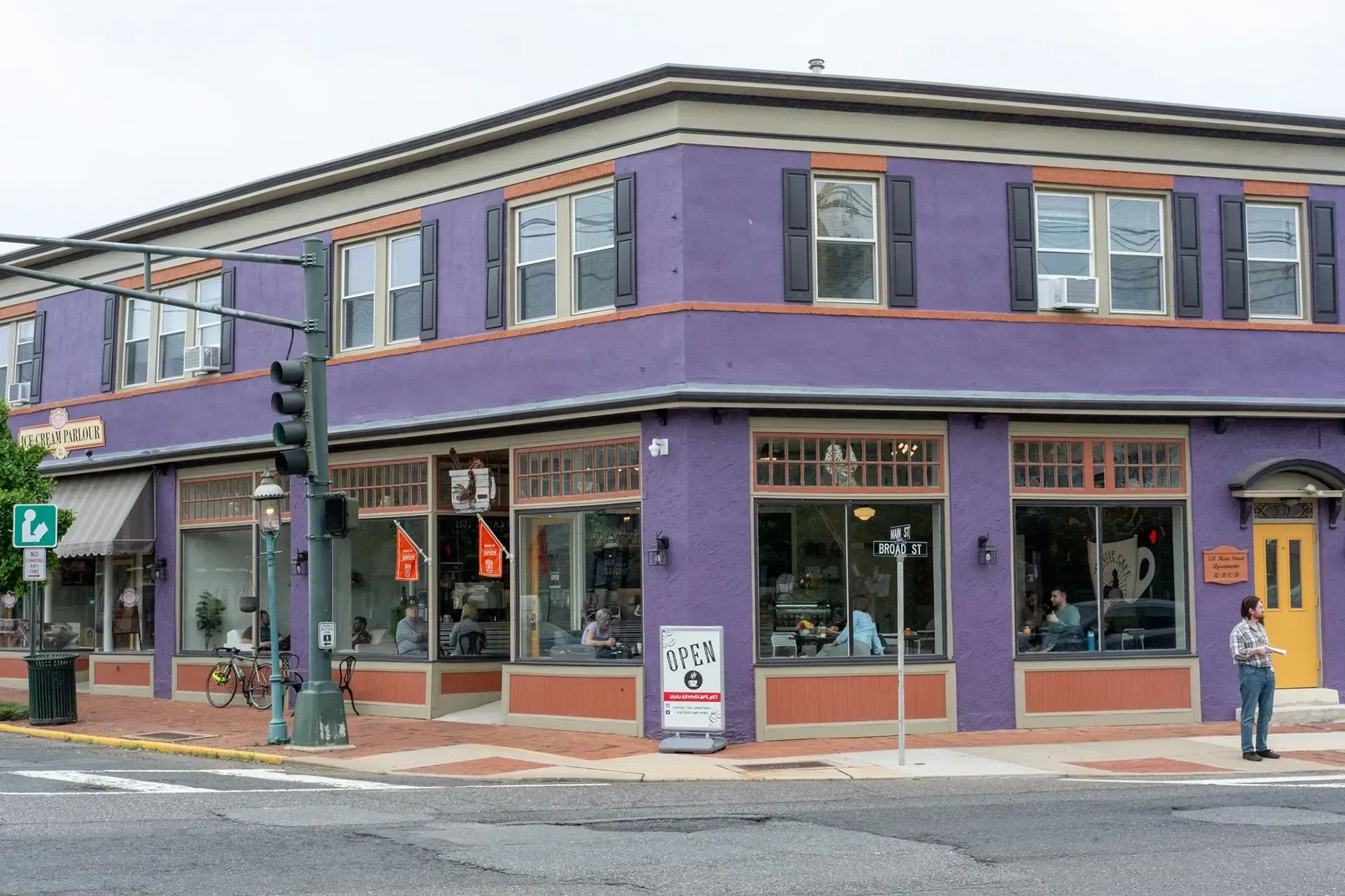 Purple corner building with large windows; street corner; people visible inside.