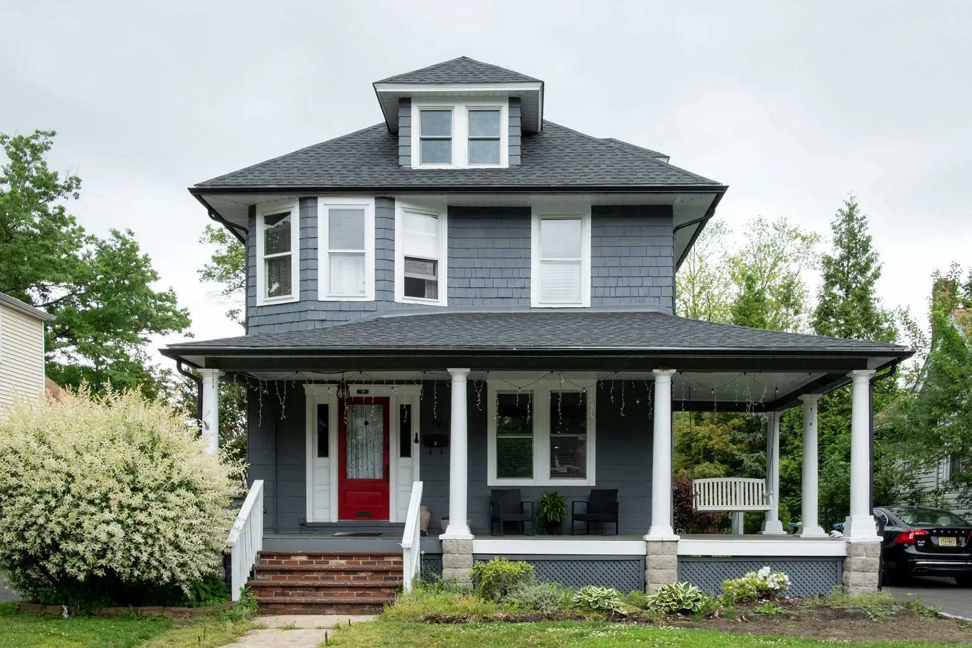 Gray house with white columns, red door, and porch swing.