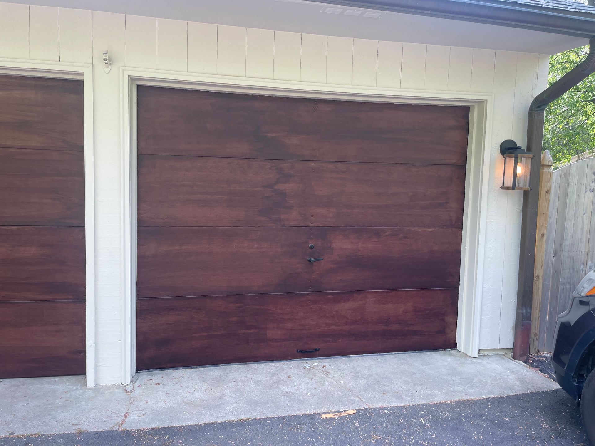 Dark brown garage door with white trim, an outdoor light, and a gutter.