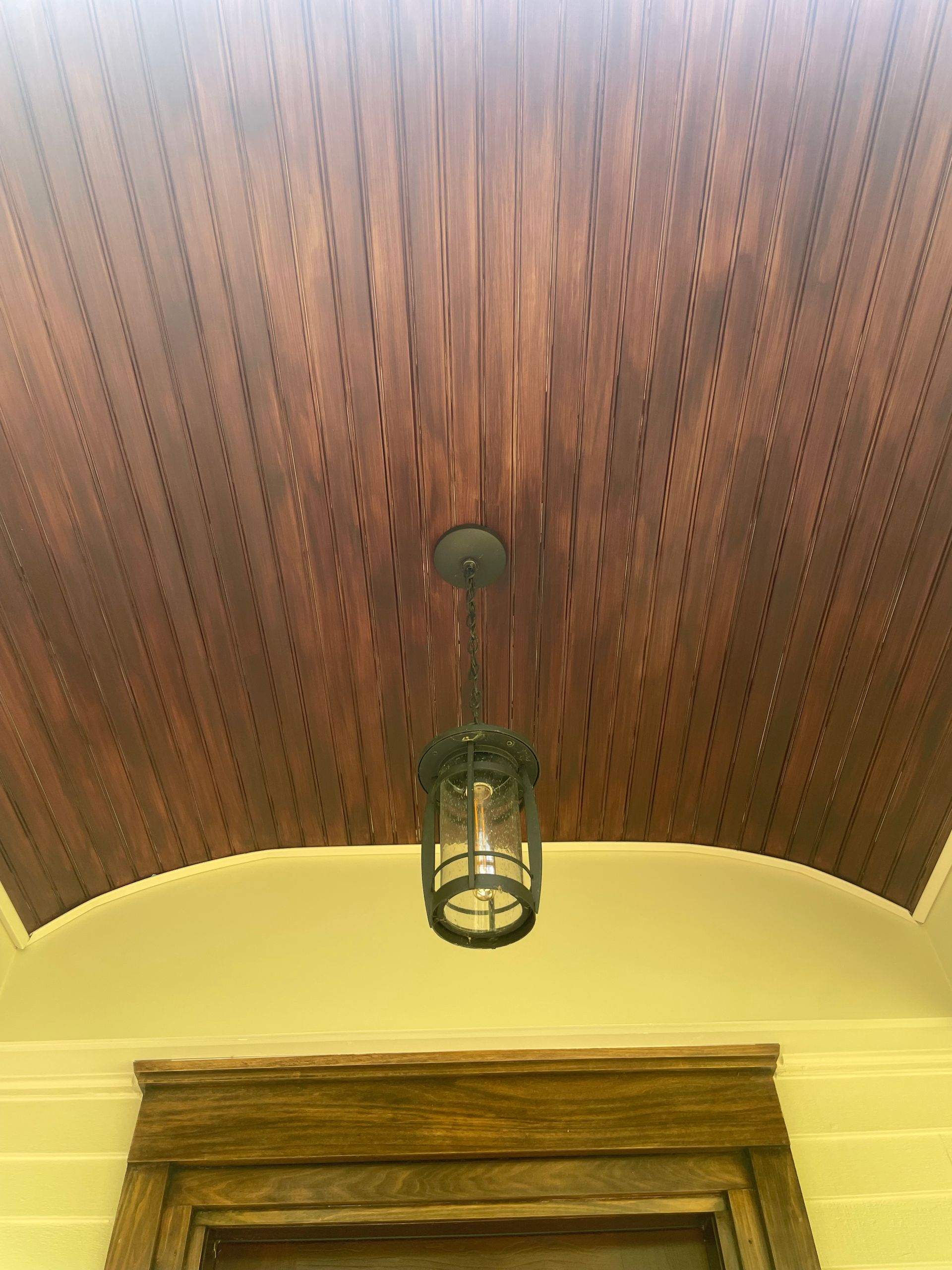 Wooden porch ceiling with recessed lighting and a hanging lantern.