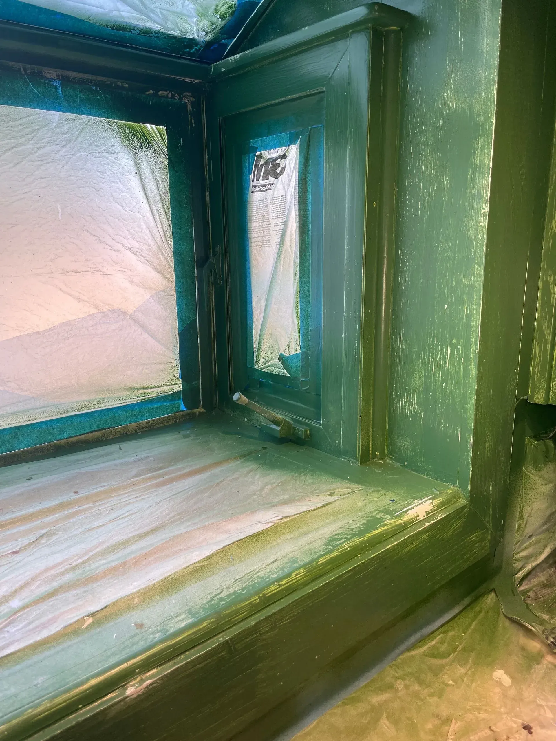 Green painted window frame with peeling paint and frosted glass.