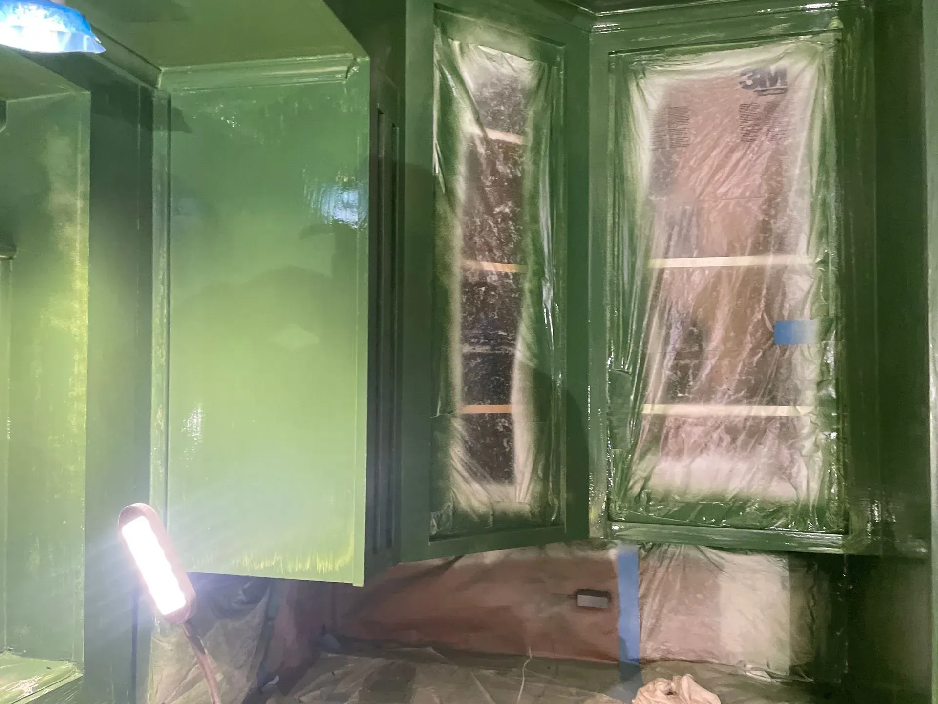 Room interior painted green, windows covered, light illuminates wall.