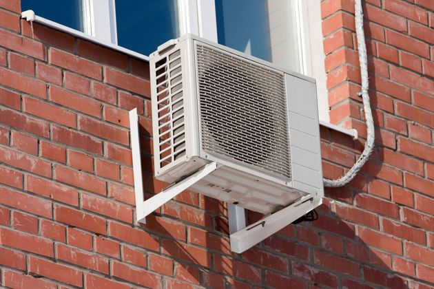 Wall-mounted air conditioner unit on a red brick building exterior