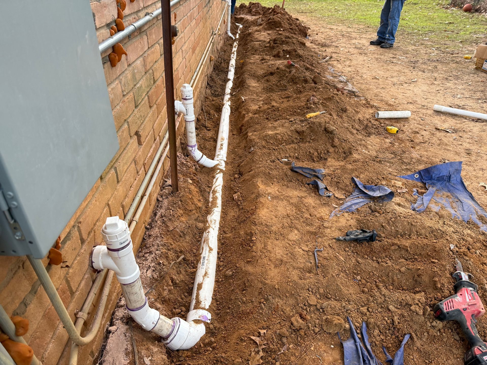 A man is standing in the dirt next to a brick wall.