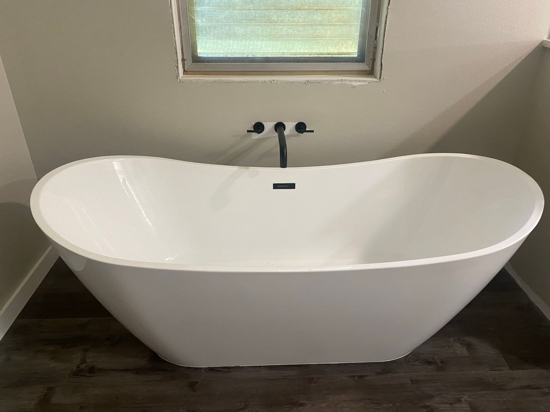 A white bathtub is sitting in a bathroom next to a window.