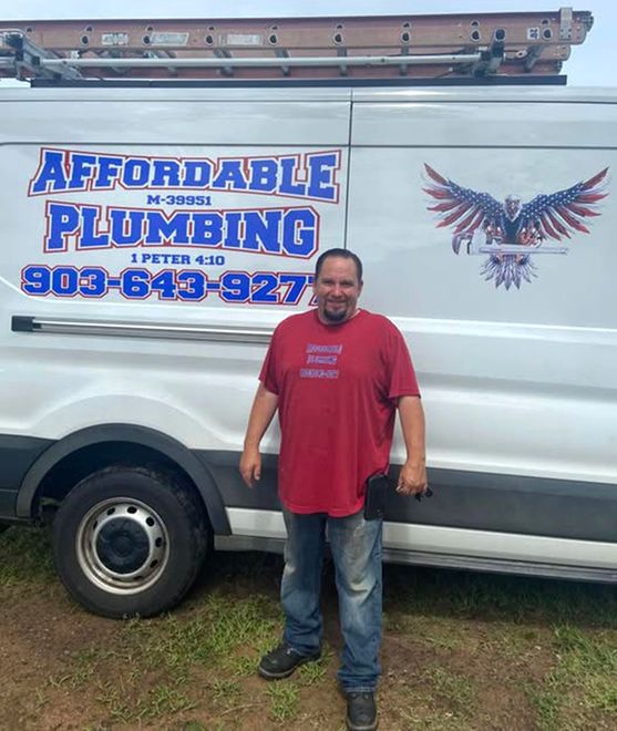 A man in a red shirt is standing in front of a white van