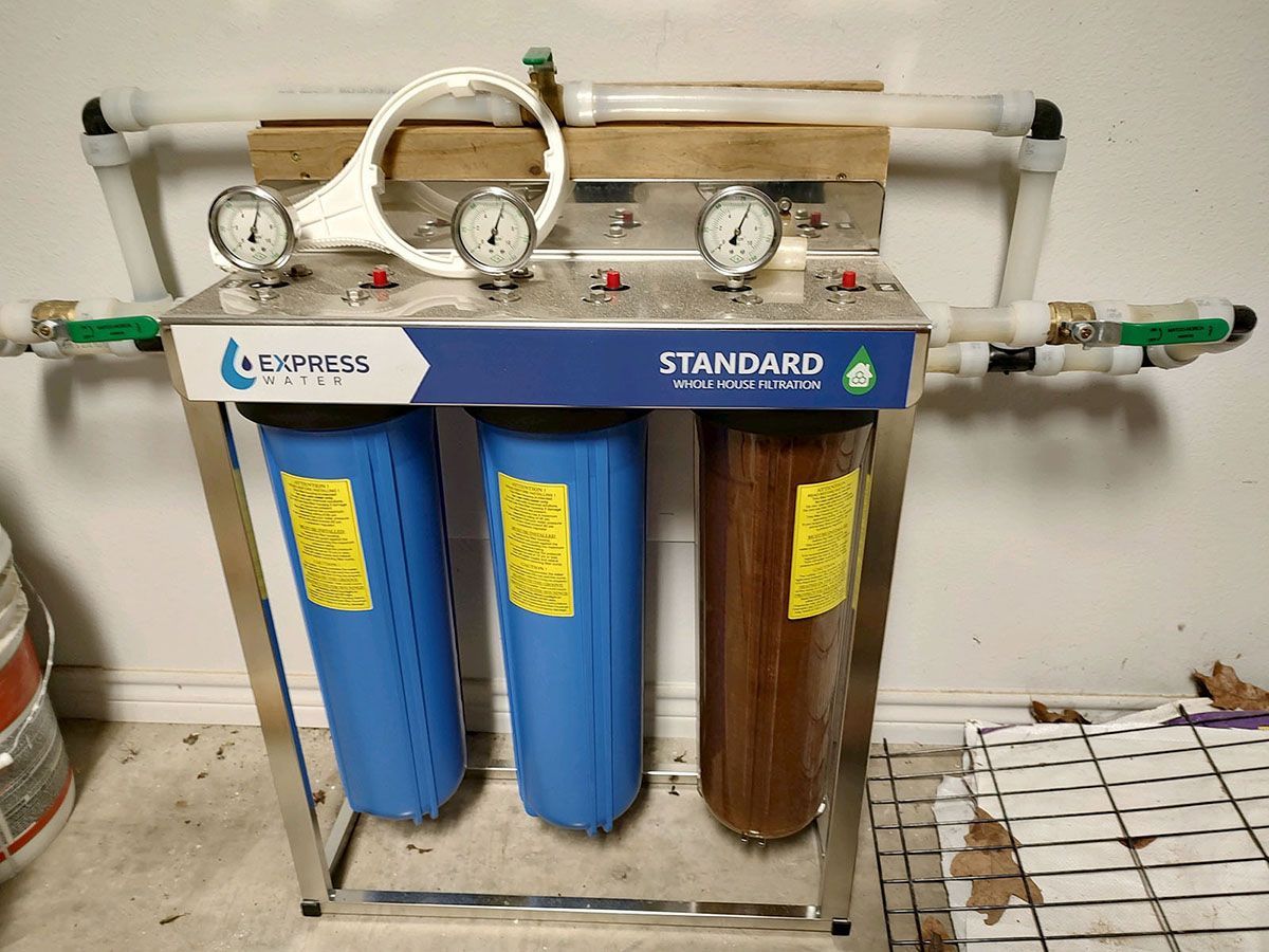 A water filter is sitting on a tiled floor next to a wall
