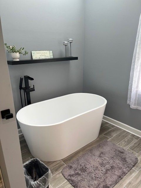 A bathroom with a bathtub and a rug on the floor